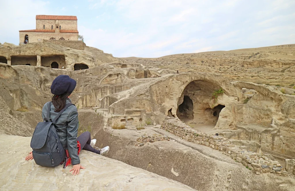 Uplistsikhe-female-visitor-sitting-rock-uplistsikhe-cave-city-ruins-located-near-gori-town-georgia