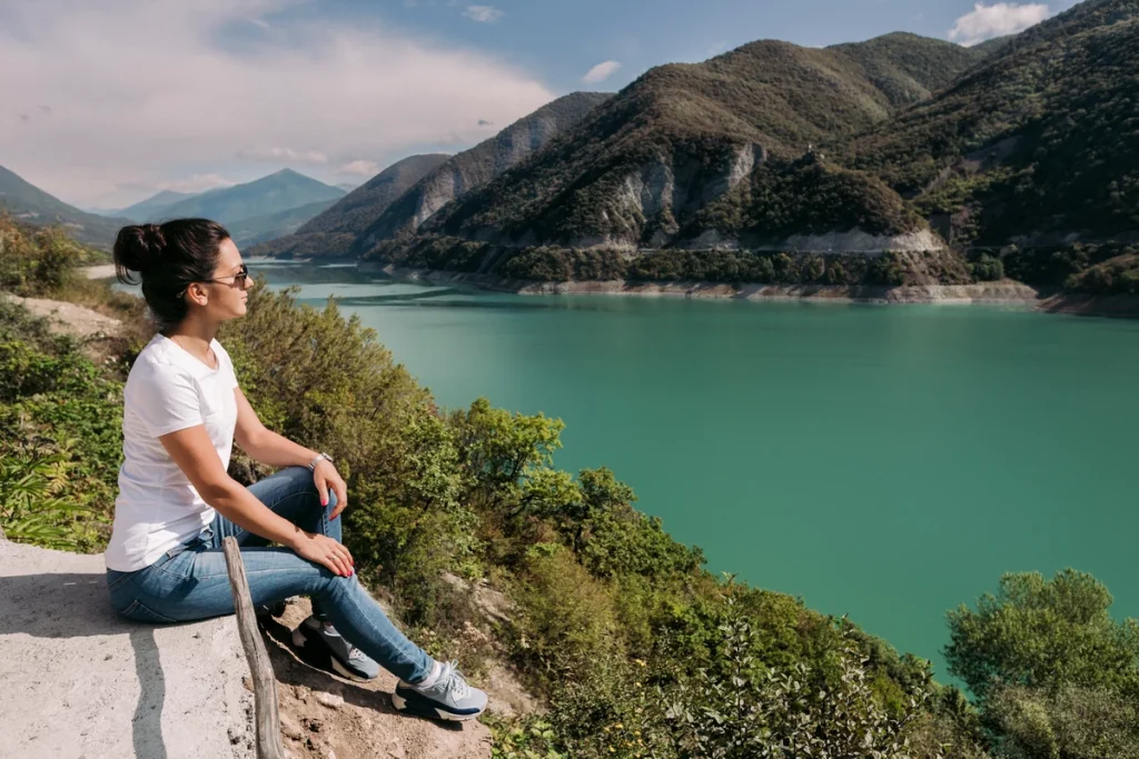 Zhinvali-young-female-traveler-sits-looks-beautiful-view-zhinvalskoe-reservoir-georgia